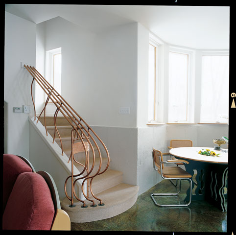 Inside this tree-sheltered home is a curvilinear, custom-designed stair railing of copper tubing that echoes the sass and “brass” of its imaginative architect owner.
